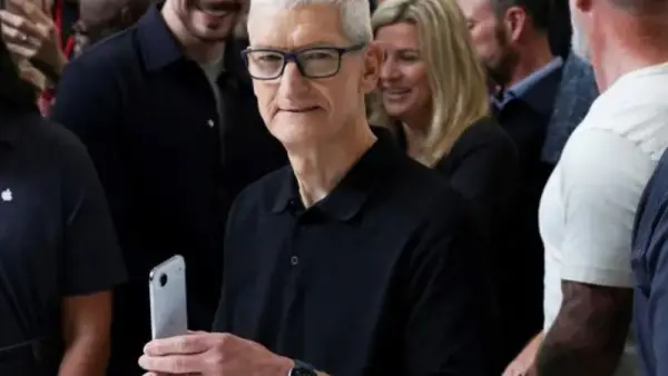 تيم كوك الرئيس التنفيذي لشركة أبل يحمل هاتفي آيفون آير (المصدر: رويترز)